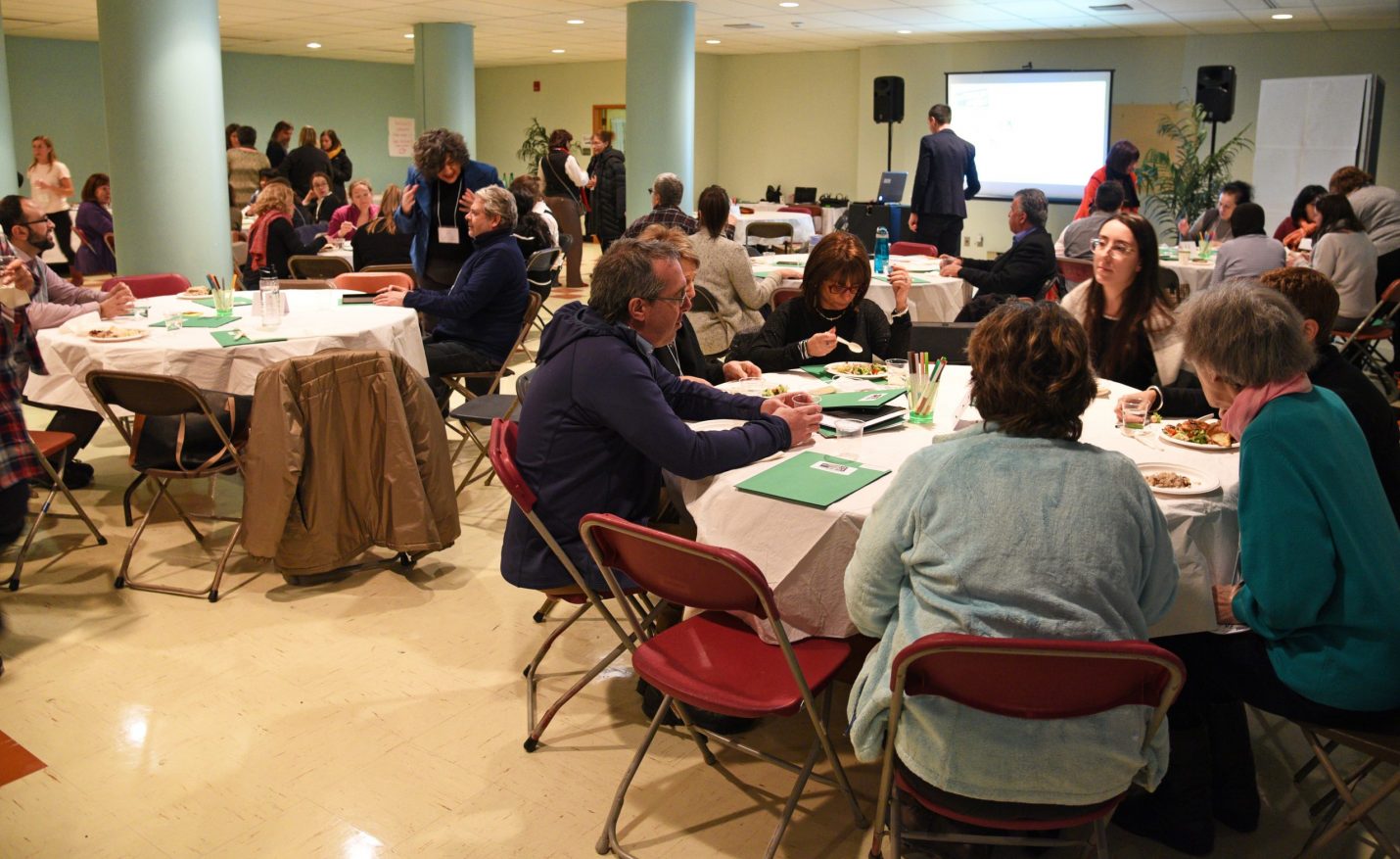 Photo ou l'on voit des personnes assises en train de parler et de travailler en concertation autour de table.